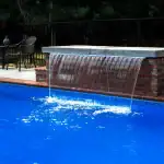 CMP Natural Wonders 48-inch white pool waterfall with back port|CMP pool waterfall water curtain close-up|Natural Wonders waterfall mounted on pool wall|CMP waterfall and fountain pool combination|Raised pool wall with CMP white waterfall feature