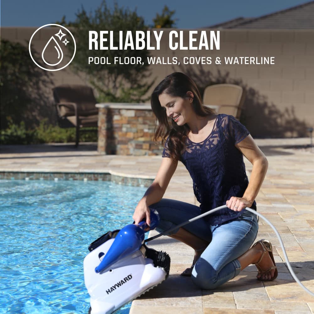 A woman kneels by a pool, using a Hayward pool cleaner for reliably clean pool floor, walls, and waterline.