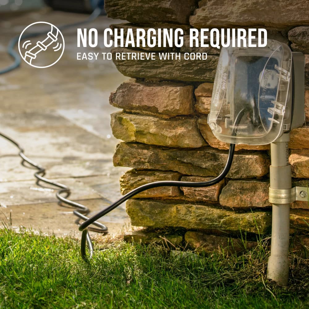 Outdoor electrical outlet with black cord plugged in, on grass near stone wall; "No Charging Required.