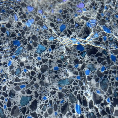 Sunlight shimmers on Midnight Opal tiles under clear water, creating a serene scene for pools in Queens.