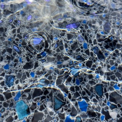 Clear water creates gentle ripples over gleaming Midnight Opal tiles in this NY pool on Long Island.