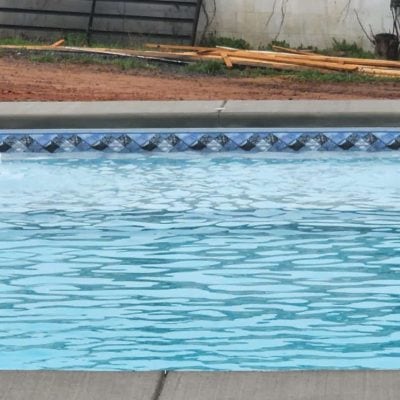A pool with fountains and a tile border features a Caswell Beach Tile/Sandy Point Floor design in Long Island.