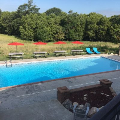 Outdoor pool area with Caswell Beach Tile flooring, lounge chairs, and umbrellas in Long Island.