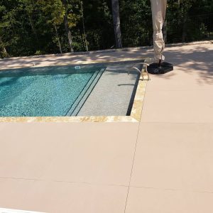 A swimming pool with Eagle Beach Tile decking, metal stairs, and a closed patio umbrella in Long Island.