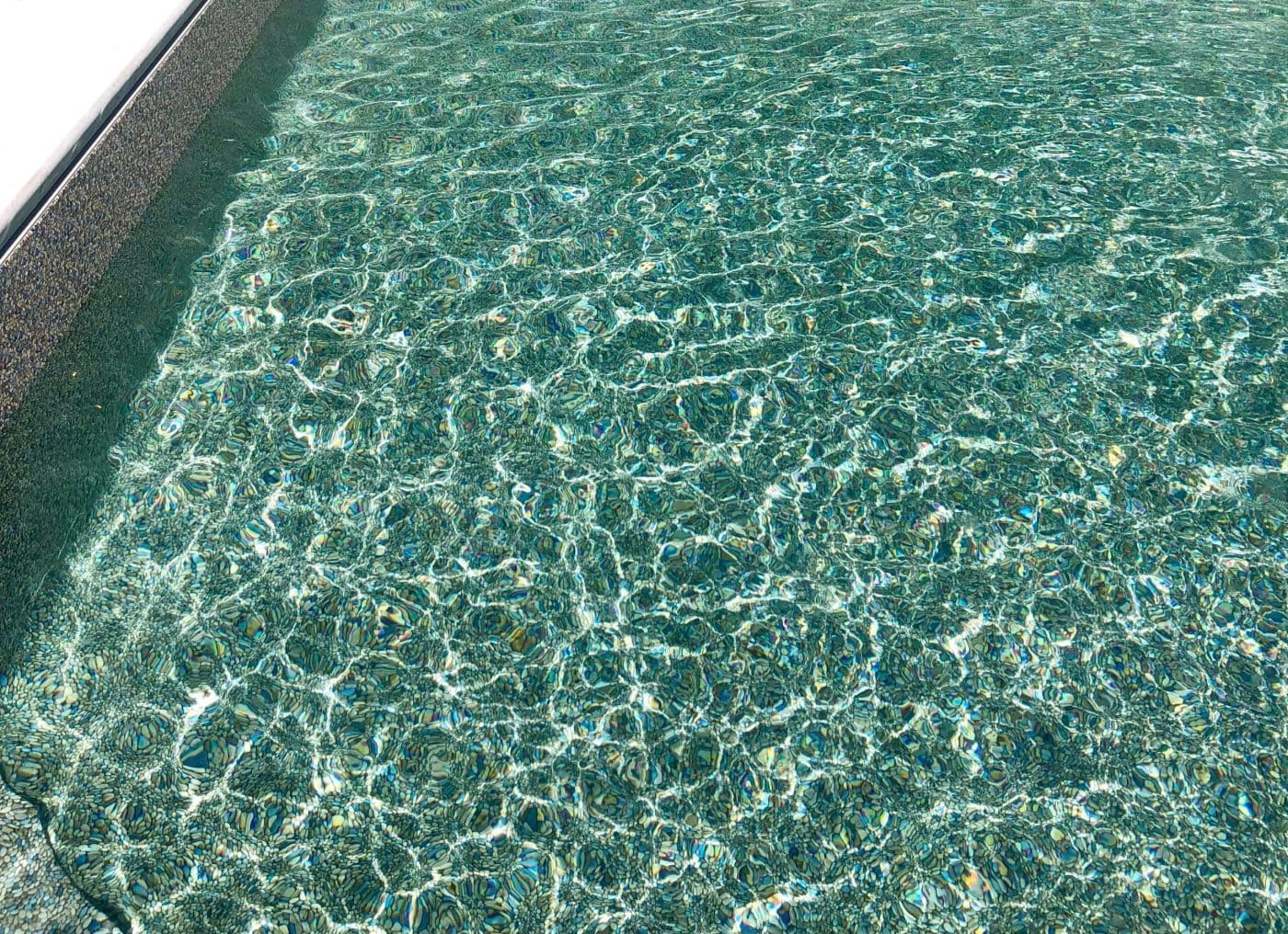 Sunlight glistens on clear water beside Eagle Beach Tile and Gold Coast Floor in Long Island, New York.