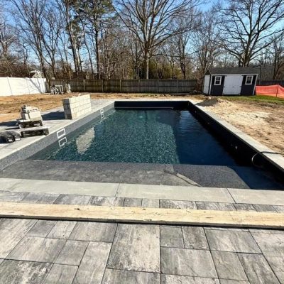 A Midnight Opal rectangular in-ground pool is being built in a NY backyard with supplies visible nearby.