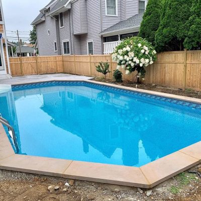 A clean blue backyard pool features Luxe Gemstone Tile and Ocean Breeze Floor in Long Island, NY.