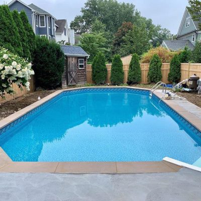 A modern backyard pool features Luxe Gemstone Tile and an Ocean Breeze Floor in Long Island, NY.