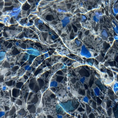 Sunlight shimmers on a rippling pool, showcasing the speckled floor and Midnight Opal in NY.
