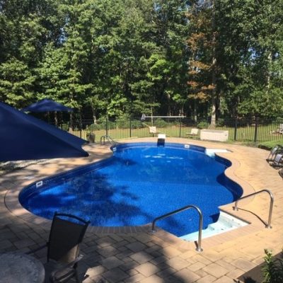A serene backyard pool area with Royal Island Tile and Sea Storm Floor, perfect for Long Island homes.