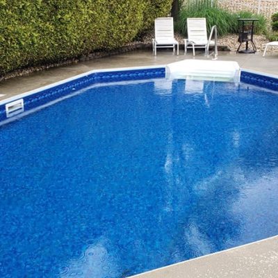 A backyard pool with a blue slide and Royal Island Tile Sea Storm floor, seen in Long Island, NY.
