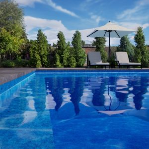 A pool with an Island Waves all over pattern, two lounge chairs, and an umbrella in Long Island.