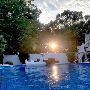 A person lounges on a white pool float at sunset, enjoying NY vibes with Valencia Tile beneath them.