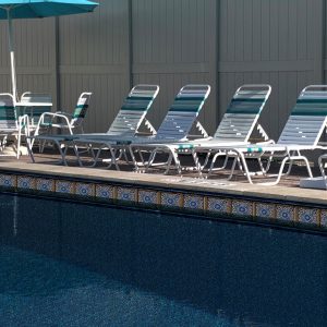 Poolside lounge chairs rest on a Pacific Tile and Sea Slate floor at a premium Long Island pool area.