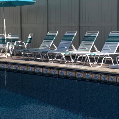 Poolside lounge chairs rest on a Pacific Tile and Sea Slate floor at a premium Long Island pool area.