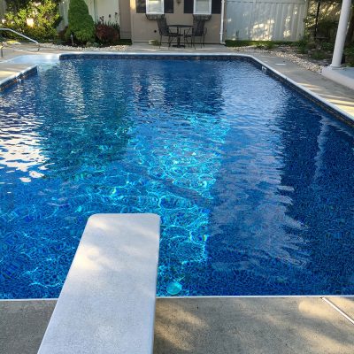A backyard pool in Long Island features Sandy Cay Tile and Runaway Bay Floor for a stylish, modern look.