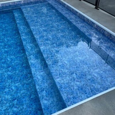 A clear NY swimming pool with wide, shallow steps, featuring Moonstone Bay pool supplies nearby.